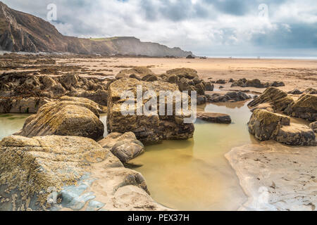 One of the many rock formations allows a deep pool to form on the expansive open beach at Sandymouth in North Cornwall. Stock Photo