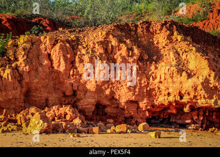 Red rocky cliff on coastline Stock Photo