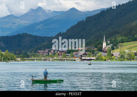 A fisherman on a small boat in Weissensee lake, Austria Stock Photo