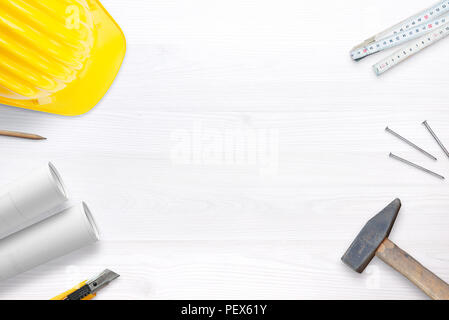 Builder helmet, tools and plans on white desk with free space fot text. Top view. Stock Photo