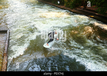 MUNICH, GERMANY - JULY 24, 2018 -  Munich, surfer riding the artificial wave on the Eisbach, small river across the Englischer Garten, in a summer mor Stock Photo