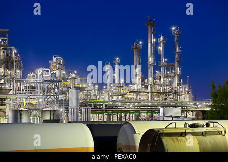 A large oil refinery with railroad cars as foreground at night. Stock Photo