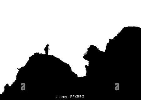 A photographer is standing on a harsh rock. Picture taken against the light and then converted to black and white. Stock Photo