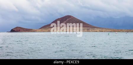 Panorama of mountain El Medano and group of windsurfers rides in atlantic ocean, Fuerteventura, Canary islands Stock Photo