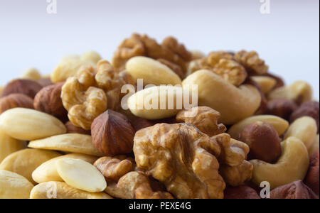Detail of nuts mixture hazelnuts almonds walnuts cashew on one pile with the white background Stock Photo