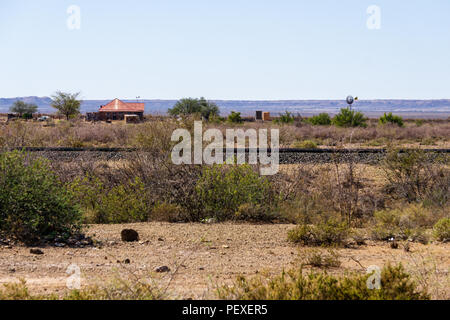 Old abandoned tin-roof shack with water tower and windmill in the Nevada desert Stock Photo