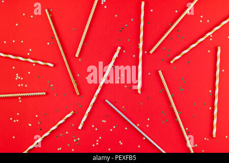 New Year or Christmas pattern flat lay top view Xmas holiday 2019 celebration drinking cocktail party straws red paper golden sparkles background. Tem Stock Photo
