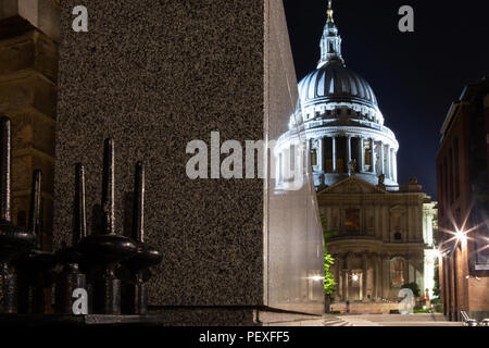 St Paul's Cathedral at night with reflections in a granite wall, and railings in foreground, City of London, UK Stock Photo