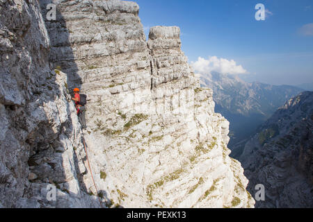 Mountain guide walking along cliff during climb of Triglav, Slovenia Stock Photo