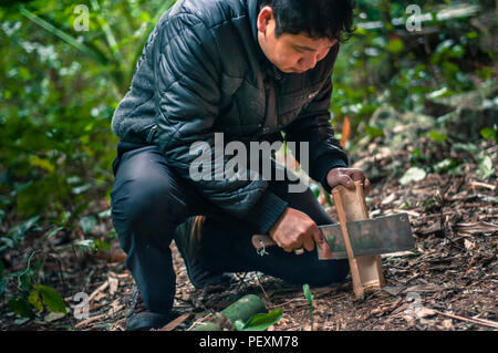 Man chopping bamboo with machete in Hidden Valley, Cat Ba Island, Quang Ninh, Vietnam Stock Photo