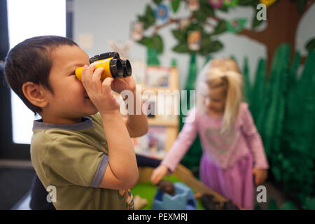 Boy using toy binoculars in classroom Stock Photo