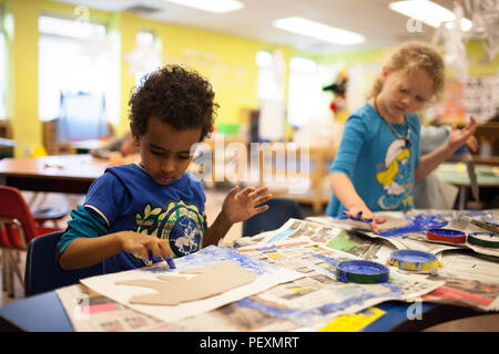 Schoolchildren finger painting in classroom Stock Photo