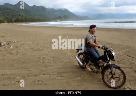 Asian man on motorcycle on beach, Banda Aceh, Sumatra, Indonesia Stock Photo