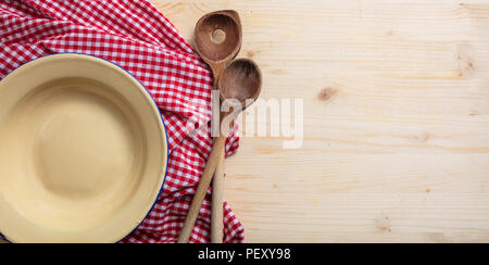 Rustic place setting. Empty plate, kitchen utensils and red tablecloth on wooden table, top view, copy space Stock Photo