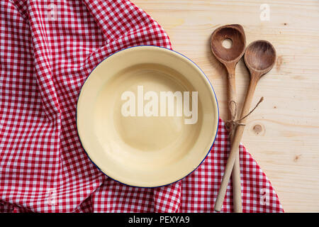 Rustic place setting. Empty plate, kitchen utensils and red tablecloth on wooden table, top view, copy space Stock Photo