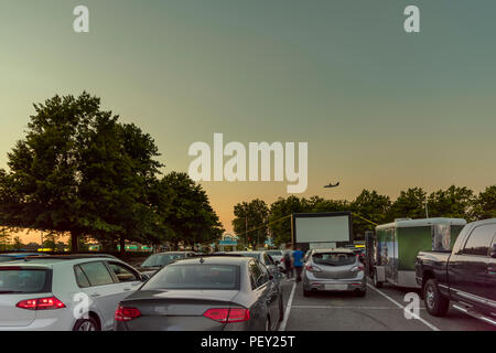 Cars in city parking with an inflatable screen of a summer cinema, waiting for a movie on a warm summer evening Stock Photo