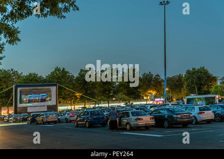 Cars in city parking with an inflatable screen of a summer cinema, waiting for a movie on a warm summer evening Stock Photo