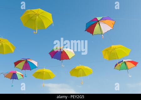 Symbol of summer, many open multi-colored umbrellas on sky background Stock Photo
