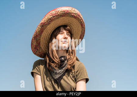 Young beautiful girl in sombrero and bandana dressed up as bandit of gangster. Female person in traditional mexican hat posing as mexico festive symbo Stock Photo