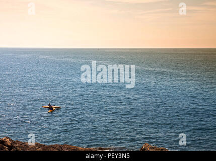 two people in kayak pause on the sea near the rocky coast Stock Photo