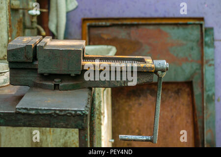 Old metal manual vise tool, in the home workshop on workbench. Vice is tool for industrial works. Selective focus. Close-up. Stock Photo