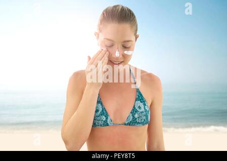 Woman applying sunscreen to her face. Stock Photo