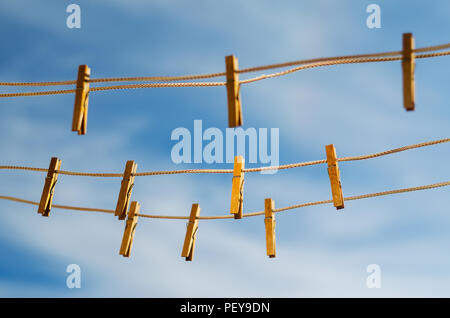 Wooden clothespins on a clothesline against a blue sky background Stock Photo