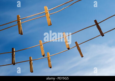 Wooden clothespins on a clothesline against a blue sky background Stock Photo