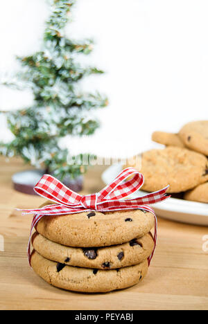 chocolate chip cookies tied with red and white gingham ribbon and bow with Christmas tree Stock Photo