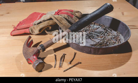 old rusty hammer and construction gloves laid on wooden board in studio Stock Photo