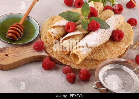 Homemade crepes served with fresh raspberrries and powdered sugar on rustic table Stock Photo