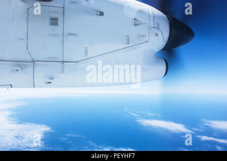 Airplane rotor moving in air flying over the clouds in the blue sky Stock Photo
