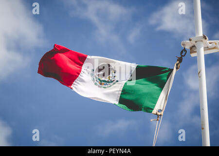 Mexican flag flying on the top of a ship on a sunny day. Stock Photo