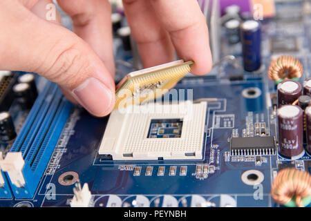 Technician installing CPU chip microprocessor to socket on motherboard Stock Photo