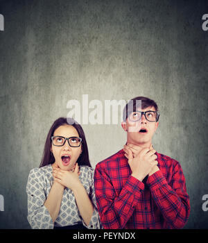 Young man and woman suffocating themselves looking irritated with being in relationship and looking up Stock Photo