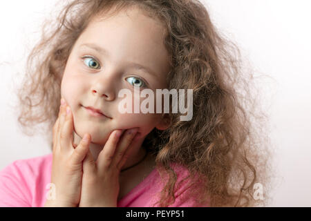 sweet little girl with hands on the chin looking at the camera close up cropped photo Stock Photo