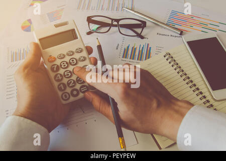 Man hand using a financial calculator and Financial data analyzing on desk at home Stock Photo