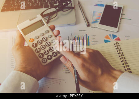 Man hand using a financial calculator and Financial data analyzing on desk at home Stock Photo