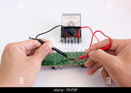 Technician hand with multimeter probes repairing circuit board Stock Photo