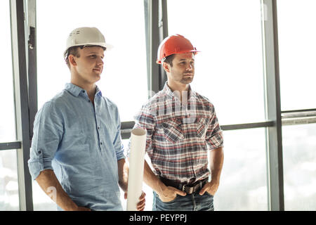 cheerful handsome constructors are resting in the room with panorama window. side view photo Stock Photo