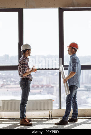 construction workers are working together on business plan in the room with panorama window. side view shot Stock Photo