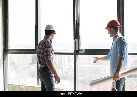 two builders are checking the new panorama windows in the office building Stock Photo