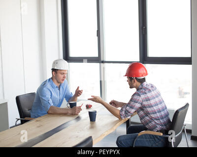 professional constructors are sharing with experience while drinking tea. panorama window on the background of the photo. side view shot Stock Photo