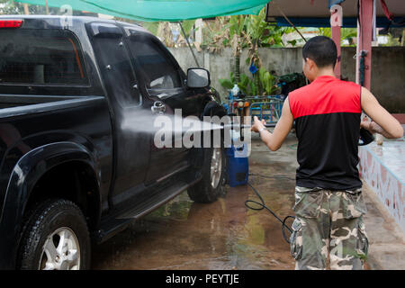 Man washing black pickup truck car with high pressure washer Stock Photo