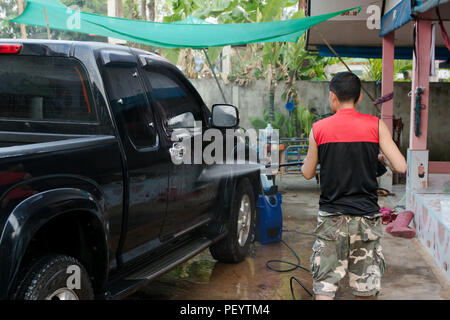 Man washing black pickup truck car with high pressure washer Stock Photo