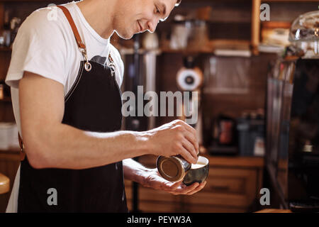 cheerful barista man preparing beverage from coffee at the cafe. closeup cropped side view photo.barista likes his work Stock Photo