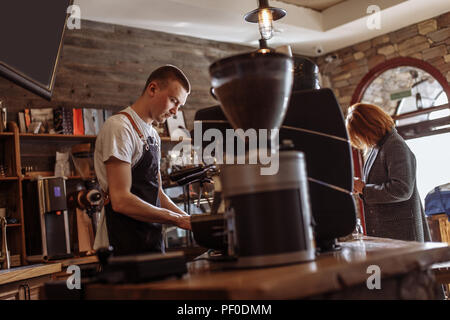 a salesman is making coffee for a woman in the coffee house with modern interior Stock Photo