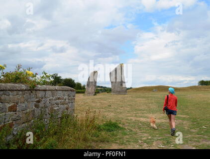 A woman walking her dog at Avebury, a monument containing three stone circles, around the village of Avebury in Wiltshire, in southwest England. Stock Photo