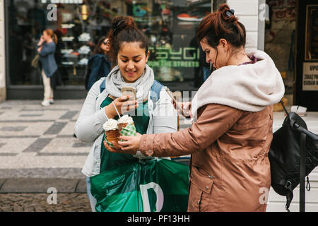 Prague, September 25, 2017: Two friends after shopping in the store stand on the street and take pictures of a traditional Czech dessert called Tridlo and make a post in social networks Stock Photo