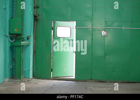 Green iron wall with half-open door Stock Photo